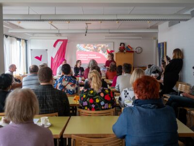 Ihmisiä kokoustamassa pöytien ääressä